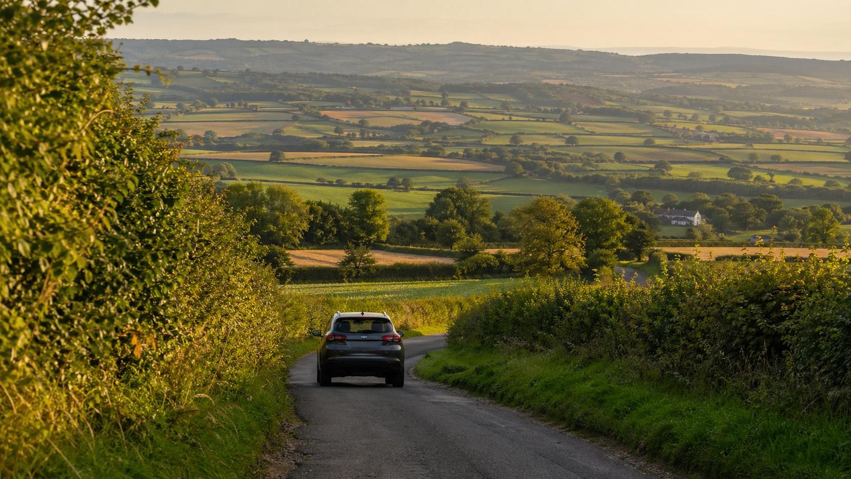 Compact rental vehicle driving along a country lane near Wellington in soft morning light